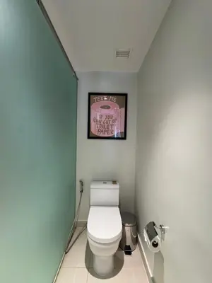 a bathroom with a toilet with a picture on the wall at Hotel Residence at Novotel in Manila