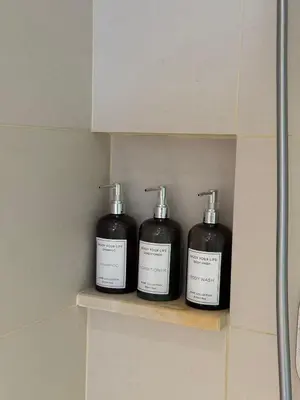 two bottles of soap sitting on a shelf in a bathroom at Hotel Residence at Novotel in Manila