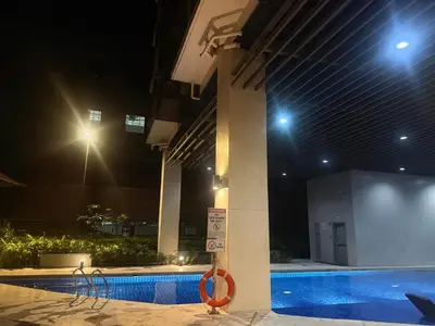 a swimming pool at night with a lifesaver next to a building at 1 Bedroom Near Mall of Asia in Manila