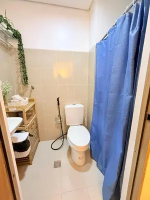 a bathroom with a toilet and a blue shower curtain at MC Haven Staycation near MOA in Manila