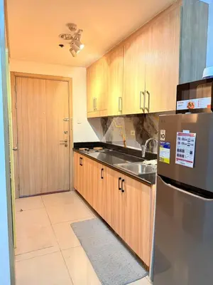 a kitchen with wooden cabinets and a stainless steel refrigerator at MC Haven Staycation near MOA in Manila