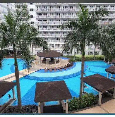 a large swimming pool with palm trees and a large building at Shell Residences Condominium Philippines, Manila, Pasay City in Manila
