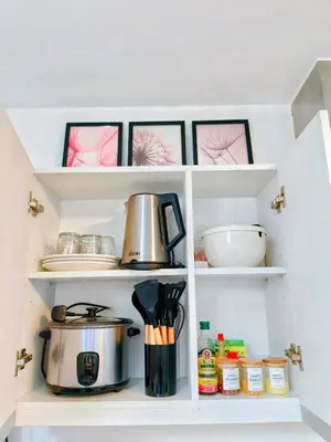 a kitchen pantry with white shelves with pots and pans at Vacation in Harmony in Manila