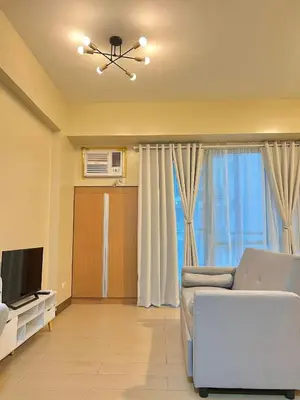 a living room with a couch and a television at CONDOTEL - Across NAIA T3 Airport with WIFI in Manila