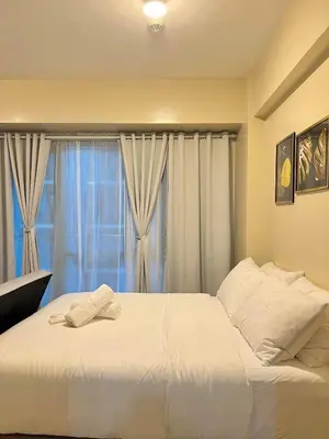 a bedroom with a large white bed with a window at CONDOTEL - Across NAIA T3 Airport with WIFI in Manila
