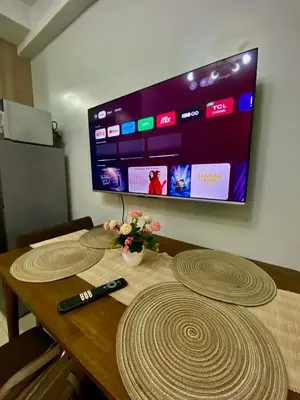 a table with a tv on the wall and a remote control at Jay's Staycation at Shore Residences Pasay in Manila