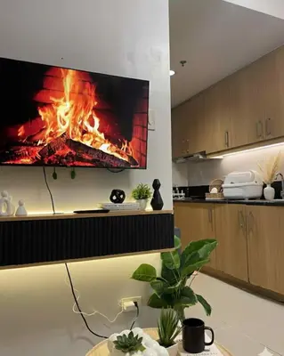 a living room with a fire fireplace on the wall at Staycation in Pasay near Moa in Manila