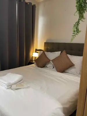 a white bed with a book on top of it at Staycation in Pasay near Moa in Manila