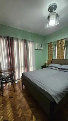 a bedroom with a large bed and some windows at Condotels by Macobs in Manila