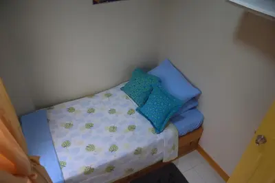 a small bed with blue and green pillows on it at CLBC Residences New home in the heart of Laguna in Biñan