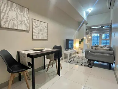 a living room with a table and chairs and a bed at Elegant Central 1BR BGC 11P Uptown Parksuites T2 in Manila