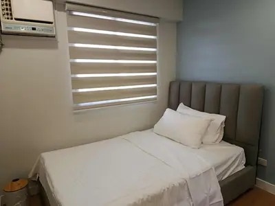 a bed in a room with a window with white sheets at Casa Alea Serenity by TinTan - Cozy 3BR Condo Unit in Manila