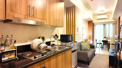 a kitchen with a sink and a living room at Cozy staycation 1BR with WiFi, Netflix and more at Shore 3 MOA by Angels Cozy Corner in Manila