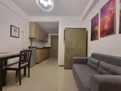 a living room with a couch and a table and a kitchen at Cozy Bedroom at SM MOA Sunset View by Manila Bay in Manila
