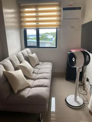 a living room with a couch and a fan at Leaf Residences in Muntinlupa