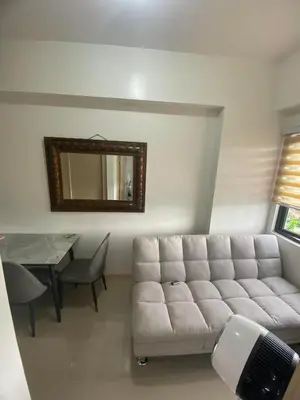 a living room with a couch and a table and a mirror at Leaf Residences in Muntinlupa