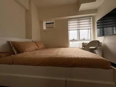 a bedroom with a bed with a window and a chair at New 1BR Condo at The Camden Place Near DLSU Manila in Manila