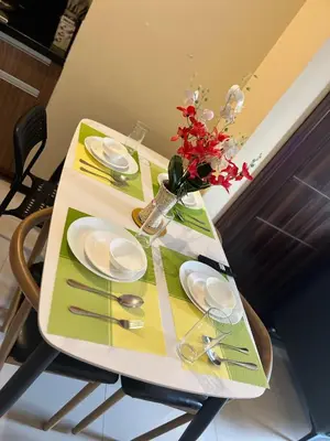 a table with plates and a vase of flowers on it at Bayfront Suite in Pasay, With Balcony, Manila Bay View, Near MOA, OKADA, PICC, Airport, WFH ready Free pool access Gym and Sauna in Manila