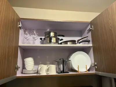 a cupboard with plates and dishes and a pot and glasses at Bayfront Suite in Pasay, With Balcony, Manila Bay View, Near MOA, OKADA, PICC, Airport, WFH ready Free pool access Gym and Sauna in Manila