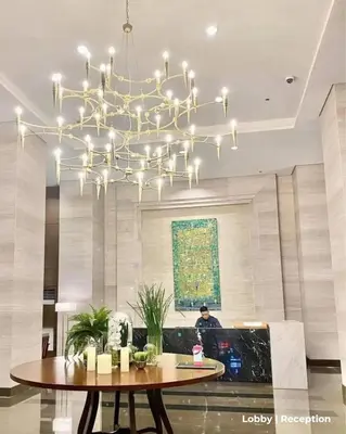 a chandelier in a lobby with a table and a person at Bayfront Suite in Pasay, With Balcony, Manila Bay View, Near MOA, OKADA, PICC, Airport, WFH ready Free pool access Gym and Sauna in Manila