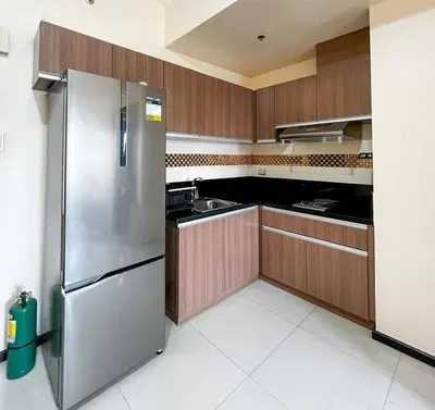 a kitchen with wooden cabinets and a stainless steel refrigerator at Family Condotels by Gerry in Manila