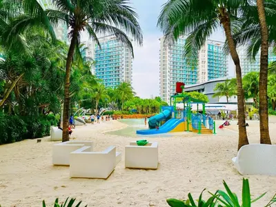 a playground on a beach with palm trees and buildings at Azure Residence by Ibiza Homes in Manila