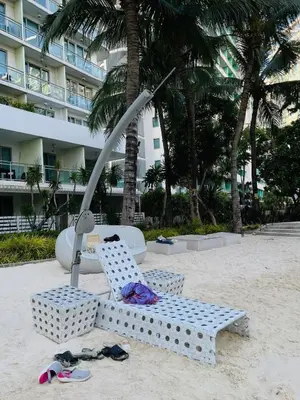 a beach chair and umbrella on the sand in front of a building at A&A staycation in Manila