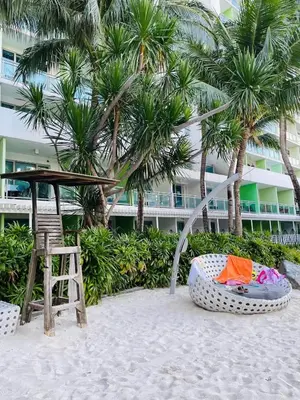 a chair and a bed on the beach with a building at A&A staycation in Manila