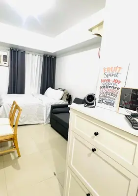 a bedroom with a bed and a desk with a couch at Jazz Residences Condo in Manila
