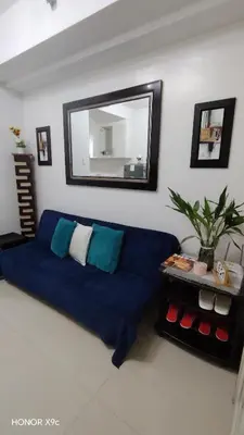 a living room with a blue couch and a mirror at Sea Residences condotel in Manila