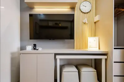 a room with a tv and a table with a clock at EJs Crib Cozy 1BR Condo at SMDC Fame Residences in Manila