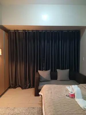 a room with two beds and a window with black drapes at Spacious Studio 3B C5 in Manila