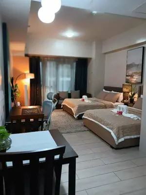a bedroom with two beds and a living room at Spacious Studio 3B C5 in Manila