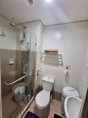 a bathroom with a shower and a toilet and a sink at Casa Kanlungan at Spring Residences Tower 3 in Manila