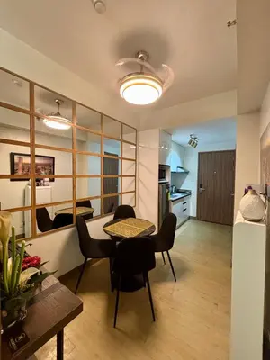 a living room with a table and chairs and a kitchen at Casa Kanlungan at Spring Residences Tower 3 in Manila