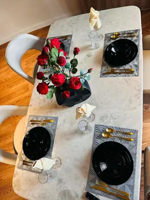 a table with two plates and a vase of red roses at Luxe 1BR Panorama Suite at Novotel Aqua in Manila