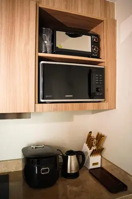 a microwave above a kitchen counter with pots and pans at Luxe 1BR Panorama Suite at Novotel Aqua in Manila