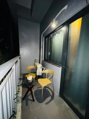 a balcony with two chairs and a table and a window at Melscape Lush Residence 1BR Unit in Manila