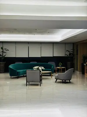 a lobby with a green couch and a table at Melscape Lush Residence 1BR Unit in Manila