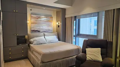 a bedroom with a bed and a chair and a window at One Bedroom Premier at Eastwood Global Plaza Luxury Residences in Manila