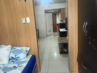 a room with a bed and a hallway with a kitchen at Sea Residences peya in Manila