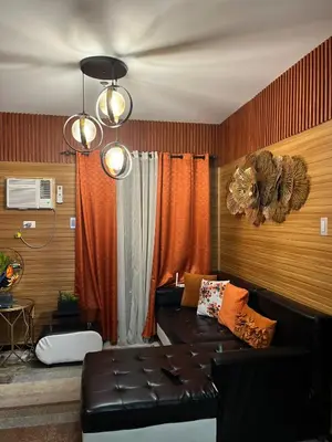 a living room with a leather couch and orange curtains at Modern 1BR Condo in Pasay With Balcony City View Free Swimming Pool Near NAIA Airport, PICC, CCP, MOA in Manila