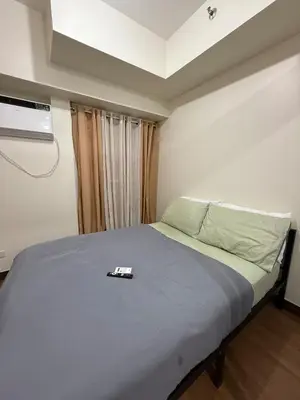 a bedroom with a bed with a remote control on it at Cozy Home with a great view in Manila