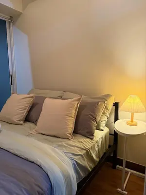 a bedroom with a bed with pillows and a lamp at Cozy Home with a great view in Manila