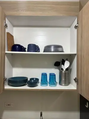 a cupboard filled with blue bowls and utensils at Airport-side Shore Staycation in Manila