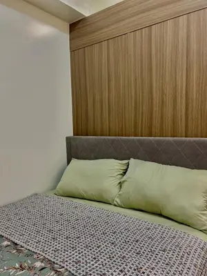 a bed with a wooden headboard in a room at Airport-side Shore Staycation in Manila