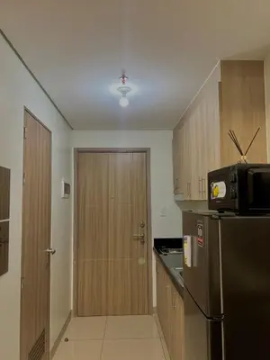 a kitchen with a stainless steel refrigerator and wooden cabinets at Airport-side Shore Staycation in Manila