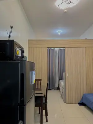 a kitchen with a table and a refrigerator and a bedroom at Airport-side Shore Staycation in Manila