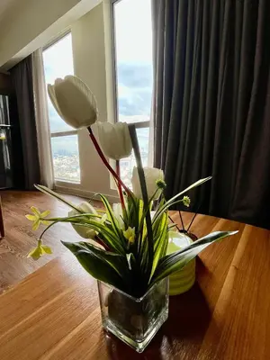 a vase with flowers on a table in front of a window at Hotel Residences at Acqua in Manila