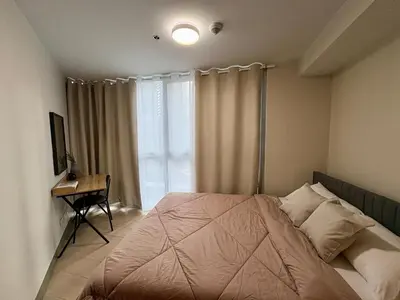 a bedroom with a bed with a desk and a window at Luxury-Styled 2BR Uptown T2 Parksuites BGC in Manila